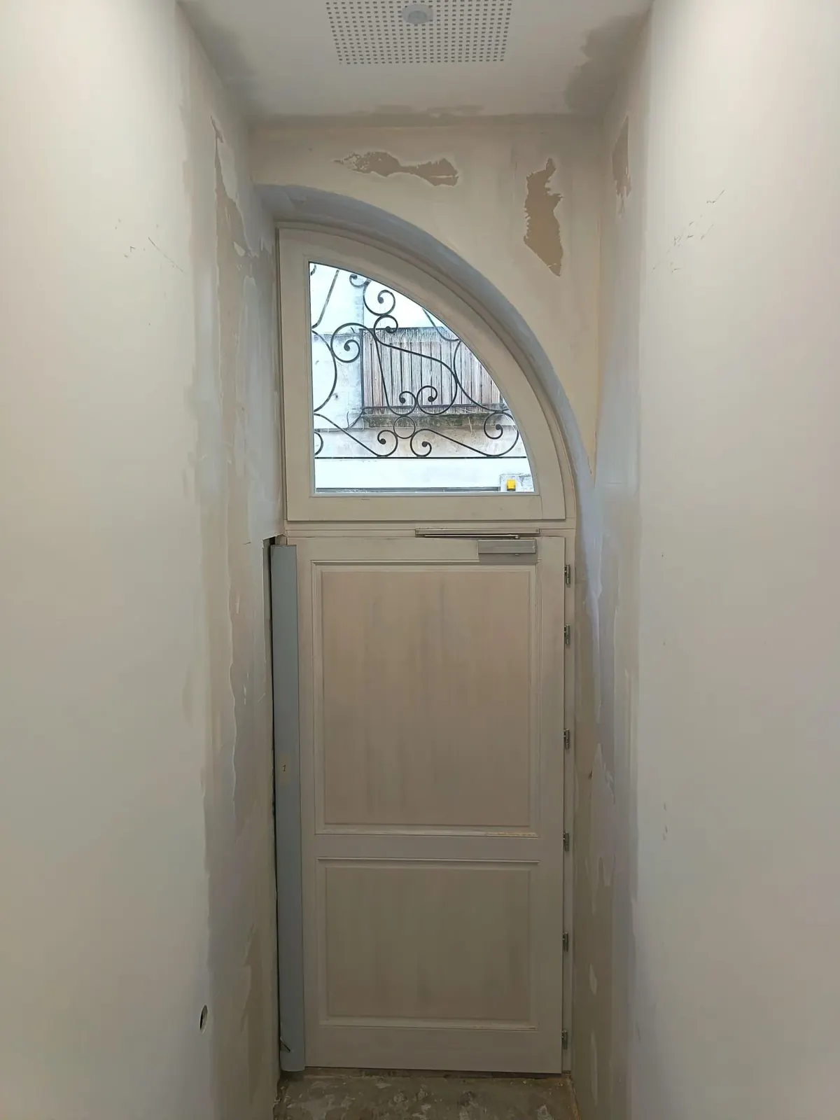 Porte d'entrée en bois cintrée posée avec son imposte vitrée