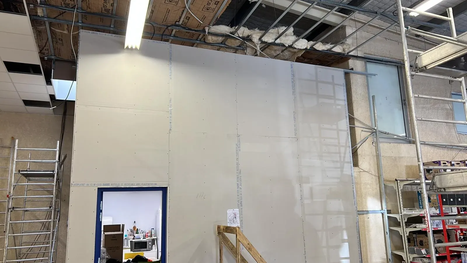 Montage d'une grande cloison en plaques de plâtre dans un local professionnel
